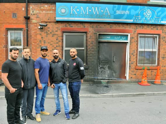 Mosque committee secretary Amjid Hussain, centre, surveys the damage with fellow worshippers