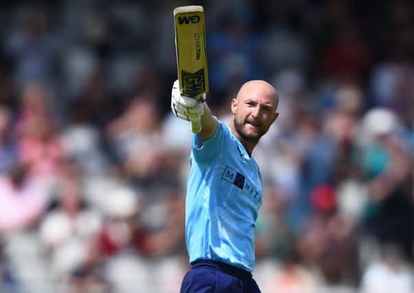 Adam Lyth of Yorkshire raises his bat after scoring a century at Old Trafford. (Photo by Nathan Stirk/ Getty Images)