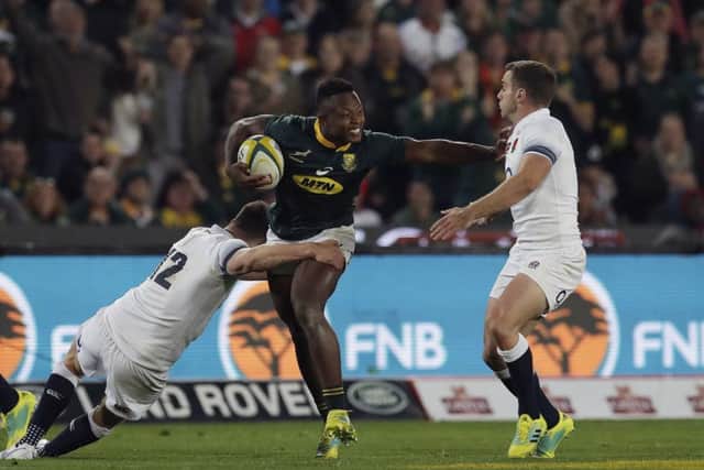 South Africa's Aphiwe Dyantyi rides a tackle from England's Owen Farrell and George Ford at Ellis Park. Picture: AP/Themba Hadebe