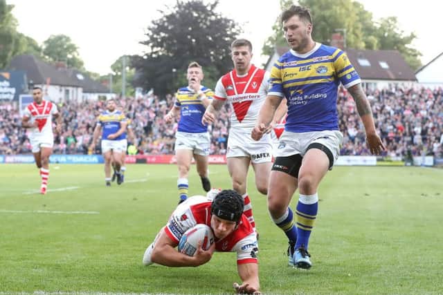St Helens' Jonny Lomax goes over for a try past Leeds Rhinos Tom Briscoe.