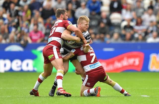 Hull FC's Brad Fash is tackled by Wigan Warriors' Sean O'Loughlin and Sam Powell. Picture: Dave Howarth/PA