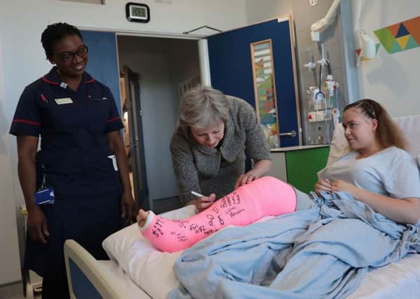 Prime Minister Theresa May signs the leg cast of patient Jade Myers, 15 from London, who broke her leg falling off a wall, during a visit to The Royal Free Hospital, north London following the announcement of  increased NHS funding.