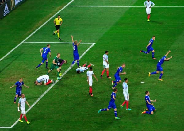 FORGETTABLE: England's players sink to their knees as Iceland's players celebrate a memorable win at Euro 2016. Picture:  Jonathan Brady/PA