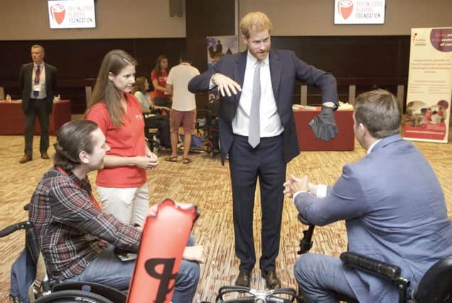 The Duke of Sussex with Karen Hood, head of the Injured Players Foundation, tries a diving glove as he meets scuba divers Tom Horay (left) and Tom Hugues