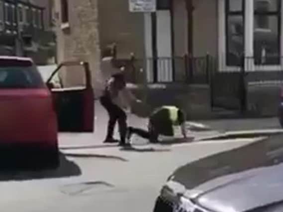 The officer can be seen being pushed to the ground