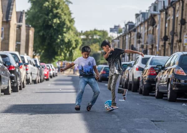 Zaheer Shahid, and Naeem Majid, having fun playing football in the middle of a side street in Huddersfield. 
Picture: James Hardisty