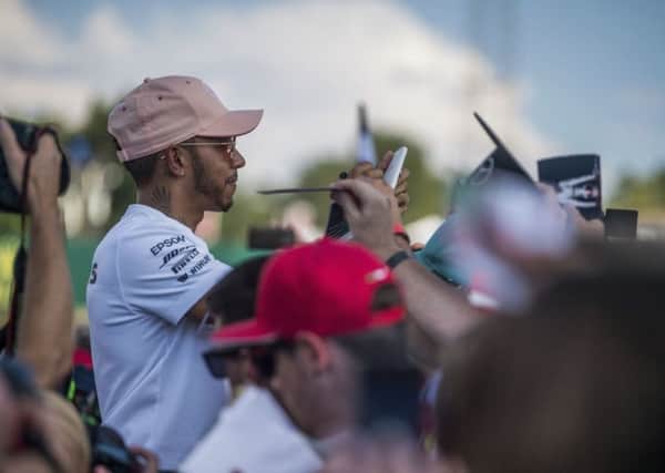 Mercedes driver Lewis Hamilton signs autographs for fans on the Hungaroring circuit. (Zoltan Balogh/AP)