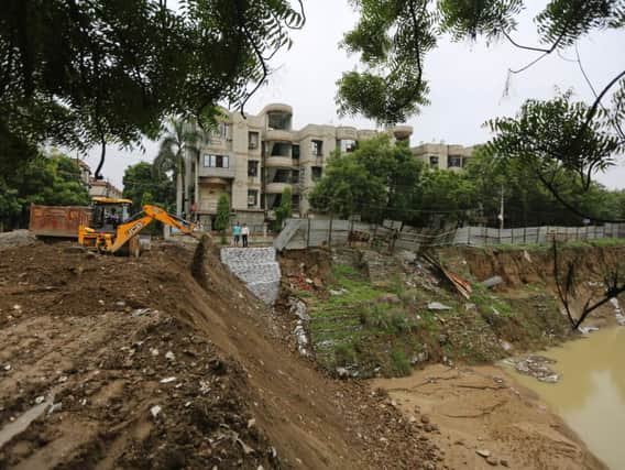An earthmover fills up a road which caved in during heavy rainfall near Ghaziabad, in the northern Indian state of Uttar Pradesh, Saturday, July 28, 2018. Dozens of people have been killed this week as monsoon rains triggered house collapses and flooded wide swaths of land in northern India, officials said Saturday. (AP Photo/Altaf Qadri)
