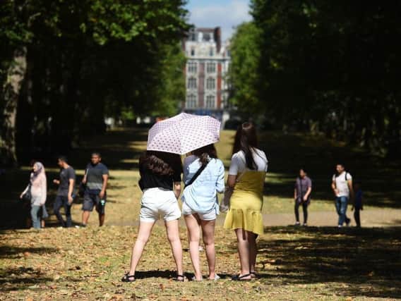 Three women pose for a photograph under an umbrella in Green Park, London, as another blast of hot weather is set to hit parts of the UK.  Photo: Kirsty O'Connor/PA Wire