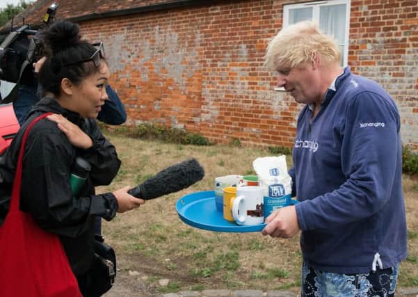 Boris Johnson brings tea for the press to drink outside his house in Thame as controversy over his comments on burkas continued.