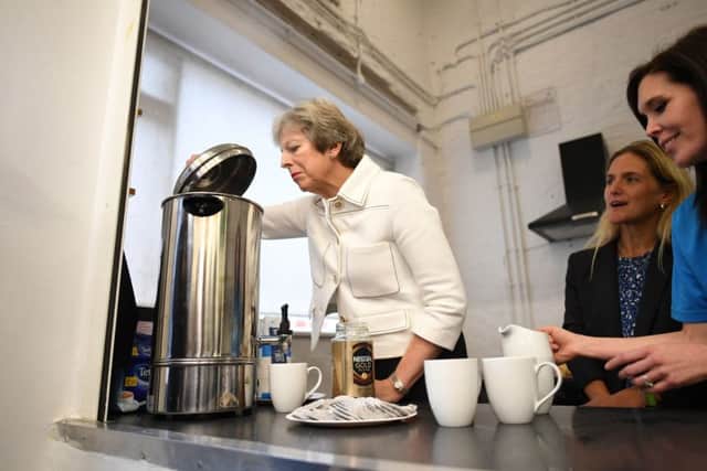 Prime Minister Theresa May peers into a hot water urn during a meeting at a social group in Vauxhall from a charity working to combat loneliness at the launch of the first loneliness strategy.  With her is Kim Leadbeater, sister of murdered MP Jo Cox.