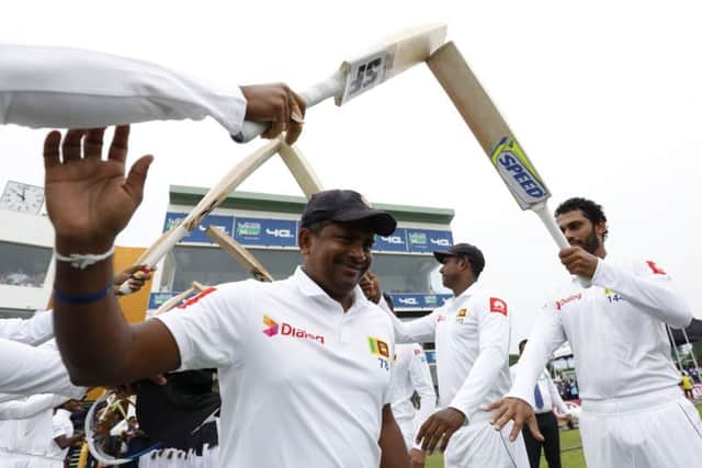 Sri Lanka's spin bowler Rangana Herath waves as he is greeted with an arch of bats while he enters the field for the last match of his test cricket career, the first test cricket match between Sri Lanka and England, in Galle, Sri Lanka. (AP Photo/Eranga Jayawardena)