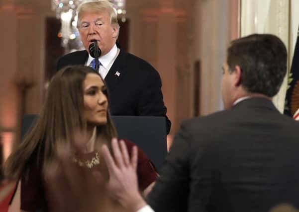 As President Donald Trump watches, a White House aide takes the microphone from CNN's Jim Acosta, during a news conference in the East Room of the White House.