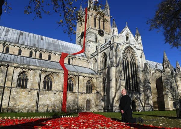 Poppies cascade down the side of Selby Abbey. Pictured verger Andrew Twineham.