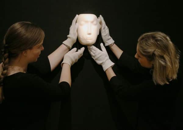 Members of staff at Bonhams in London look at a Mask sculpture by Henry Moore, before it is offered at auction. The work is one of 12 known, small carvings by Moore titled Mask, and is the only one carved from alabaster. It is estimated to fetch Â£1m to Â£1.5m.
