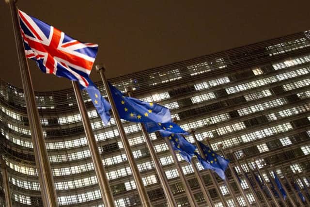 The Union Flag and EU flags flap in the wind in the early morning outside of an EU summit in Brussels, Sunday, Nov. 25, 2018. The European Union removed the last major obstacle to sealing an agreement on Brexit after Spain said it had reached a deal with Britain over Gibraltar. (AP Photo/Virginia Mayo)