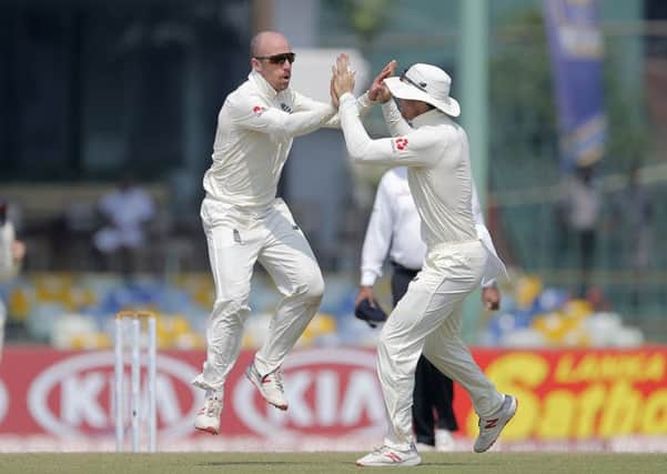 England's Jack Leach, left, celebrates taking the wicket of Sri Lanka's Lakshan Sandakan in Colombo. Picture: AP/Eranga Jayawardena.