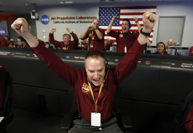 Engineer Kris Bruvold, bottom center, celebrates as the InSight lander touch downs on Mars in the mission support area of the space flight operation facility at NASA's Jet Propulsion Laboratory