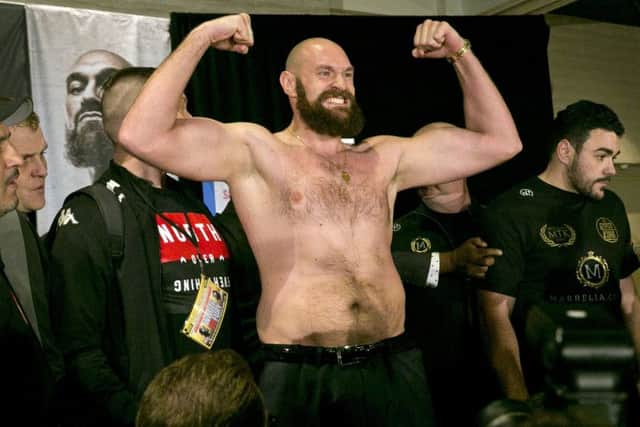 Boxer Tyson Fury flexes after exchanging words with opponent Deontay Wilder at a news conference in Los Angeles. (AP Photo/Damian Dovarganes)