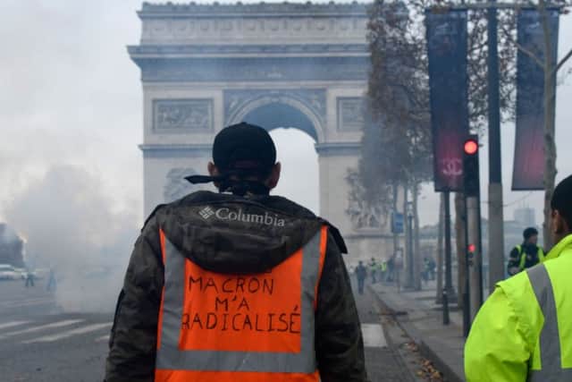 A man wears a jacket reading "Marcon radicalized me" during a protest of Yellow vests (Gilets jaunes) against rising oil prices and living costs near the Arc of Triomphe on the Champs Elysees in Paris, on November 24, 2018. (Photo by Bertrand Guay/Getty)