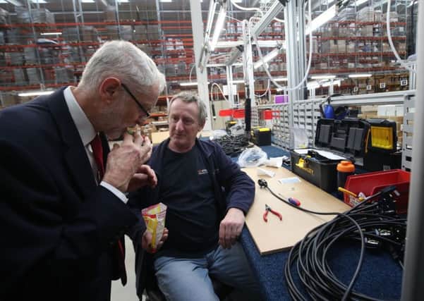 Labour leader Jeremy Corbyn is offered a Yorkshire Mixture sweet from Russ Whitehouse during a visit to OE Electrics in Wakefield.
