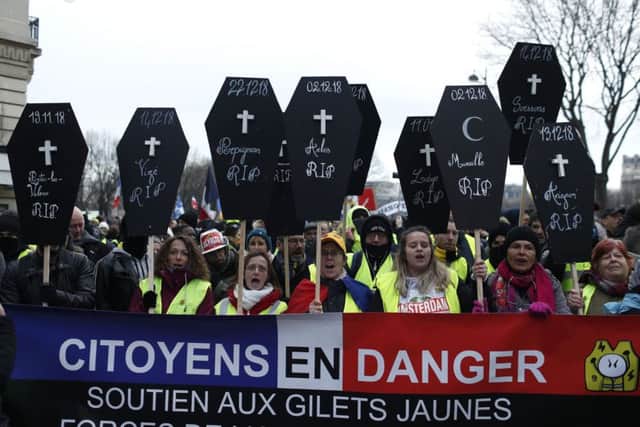 Yellow vest protesters display posters of coffins to honor hundreds injured since the movement kicked off Nov. 17, Saturday, Jan. 19, 2019 in Paris. Ten people have been killed in protest-related traffic accidents. Yellow vest protesters are planning rallies in several French cities despite a national debate launched this week by President Emmanuel Macron aimed at assuaging their anger. Banner reads: Citizen in danger, Support Yellow Vests. (AP Photo/Thibault Camus)