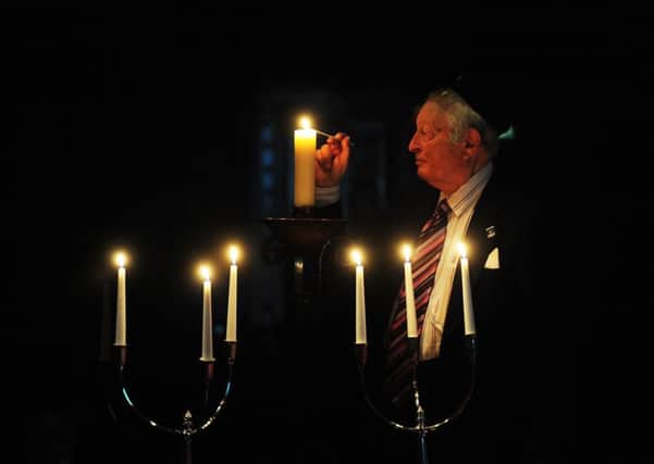 Rudi Leavor lights a candle at Leeds Town Hall today.