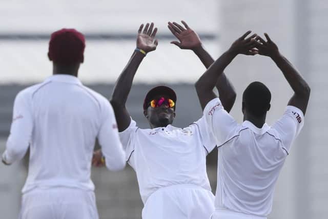 West Indies' captain Jason Holder, center, celebrates with teammate Kemar Roach, right, the dismissal of England's Ben Foakes during day two of the first cricket Test match at the Kensington Oval in Bridgetown, Barbados. (AP Photo/Ricardo Mazalan)