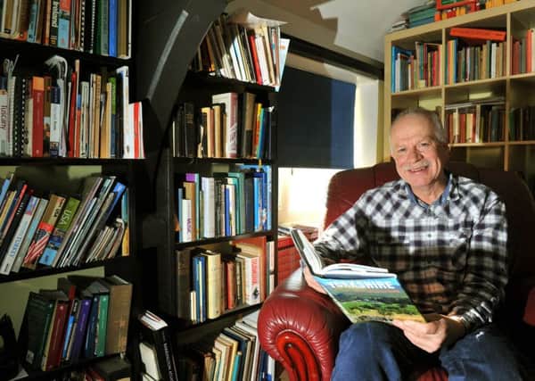 Author Julian Morgan at his home surrounded by books.