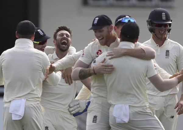 Jubilant Mark Wood is surrounded by delighted England team-mates after taking a wicket on his way to figures of 5-41 as the West Indies were dismissed for 154 (Picture: Ricardo Mazalan/AP).