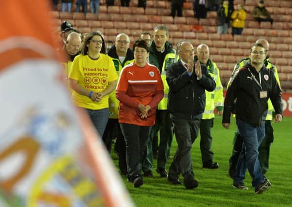 Long-serving volunteer Stephen Croft, who suffered a heart-attack shortly before kick-off when the sides were due to meet last September, leads out Barnsley and Burton Albion last night along with family and members of Yorkshire Air Ambulance (Picture: Bruce Rollinson).