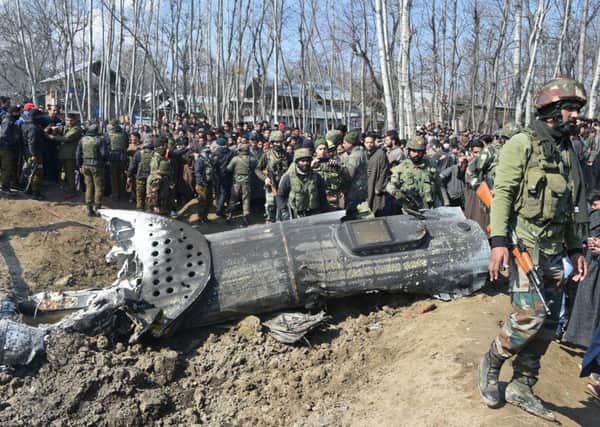 Indian soldiers and Kashmiri onlookers stand near the remains of an Indian Air Force helicopter after it crashed in Budgam district, outside Srinagar.
