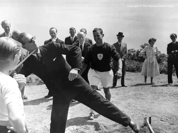 The Duke of Edinburgh throwing a javelin while meeting participants in an Outward Bound activity.