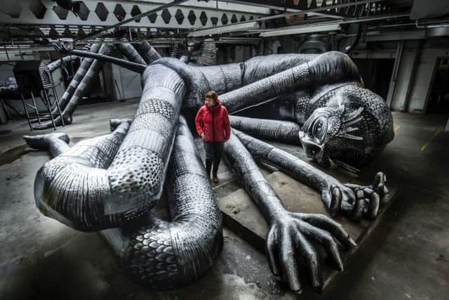 Producer Tamar Millen views one of the artworks on display during the Mausoleum of the Giants, a solo show created by artist Phlegm at the Eyewitness Works in Sheffield. Danny Lawson/PA Wire