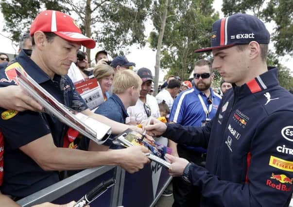Red Bull driver Max Verstappen of the Netherlands, right, signs autographs as he arrives at the track of the Australian Grand Prix in Melbourne, Australia. (AP Photo/Rick Rycroft)