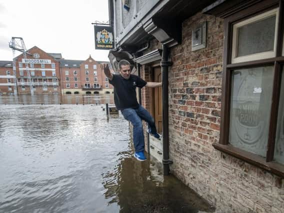 A member of staff from the Kings Arms in York jumps across flood water after the River Ouse bursts its banks. (Danny Lawson/PA Wire).