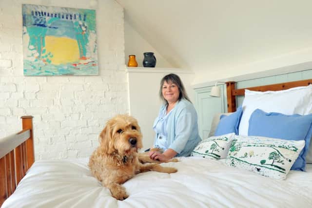 Maria Keki in the newly-created loft bedroom with her dog, Alfred. The paintng on the left is one of the first she did at university.