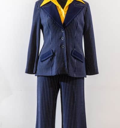 1970s trouser suit and shirt. 
Womens trouser suits first became popular in the mid-1960s with double breasted jackets, Nehru collars or epaulettes all featuring. By the 1970s lapels had spread and collars had lengthened. This blue suit with its flared trousers epitomises the look of the 70s, worn with a bright contrasting shirt with typical dagger collar, epitomises the look of the 1970s.


Picture James Hardisty.