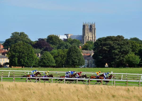 Jockeys on their mounts make their way round the bend before the final straight at Beverley Races with Beverley Minster in the background.  Picture Tony Johnson.