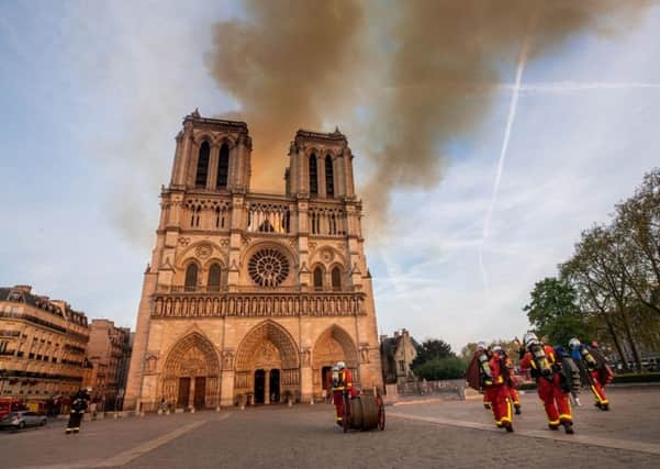 Smoke billows from the Notre Dame as Parisian firefighters rush to the scene.