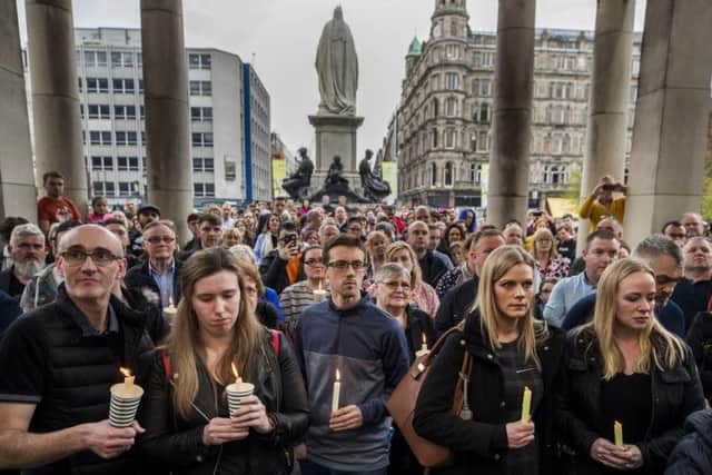 People hold candles during a vigil at Belfast City Hall in memory of murdered journalist Lyra McKee.