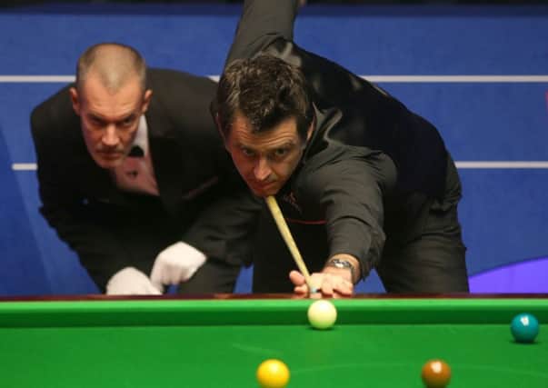 Ronnie O'Sullivan plays a shot as referee Olivier Marteel watches on.