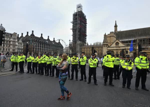 An Extinction Rebellion protester walks past a line of police officers in Parliament Square, Westminster, London. More than 1,000 people have been arrested during the climate change protests in London as police cleared the roadblocks responsible for disruption in the capital.