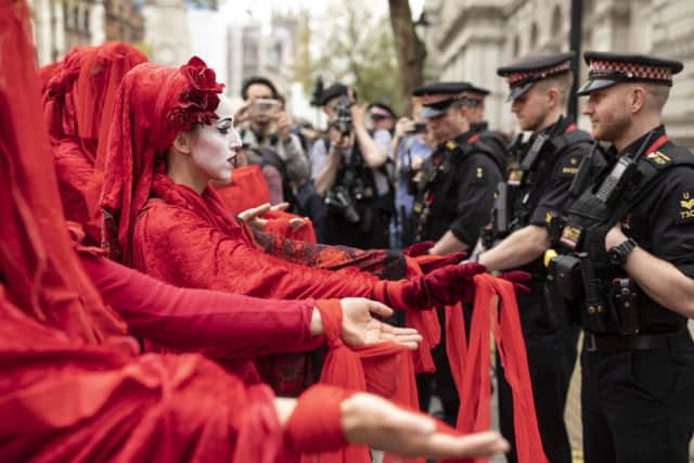 A performance group stage a silent demonstration outside Downing Street as Extinction Rebellion campaigners gather in London.