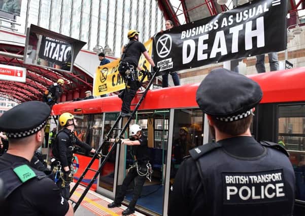Police prepare to remove climate change activists on the roof of a DLR train at Canary Wharf station during environmental protests by the Extinction Rebellion group in London.
