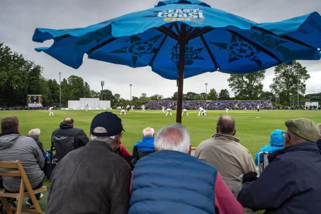 Supporters huddle from the rain at Clifton Park, York on day one of the SpecSavers County Championship match (Picture: Bruce Rollinson)