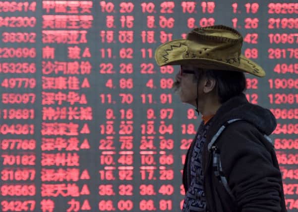 A man walks past an electronic board displaying stock prices at a brokerage house in Hangzhou in east China's Zhejiang province,  (Chinatopix via AP)