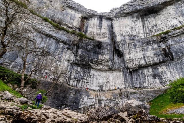 Date: 10th May 2019.
Pivcture James Hardisty.
Climbing feature at one of the UK's best climbing walls Malham Cove, in the heart of the Yorkshire Dales, near Skipton. Pictured Visitors to Malham Cove, stroll along the widing path to view the extreme sport climbers risking life ascending the near vertical cliff face of Malham cove.