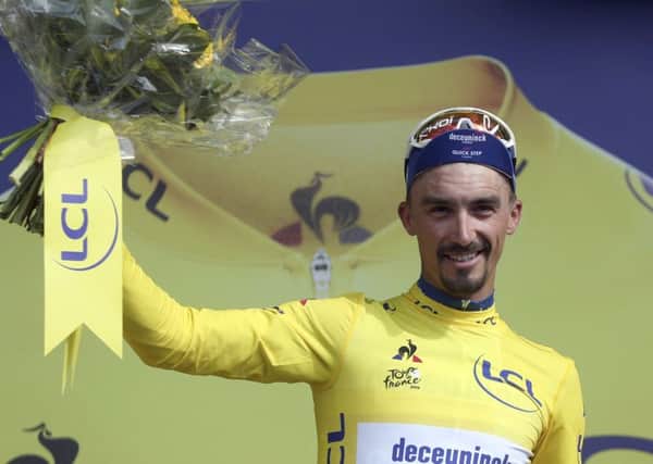 France's Julian Alaphilippe wearing the overall leader's yellow jersey celebrates on the podium after winning the third stage of the Tour de France cycling race over 215 kilometers (133,6 miles) from Binche to Epernay. (AP Photo/Thibault Camus)