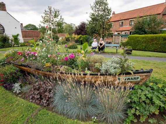 Residents in Ruswarp, near Whitby, with a rowing boat planter on the green and other floral features.